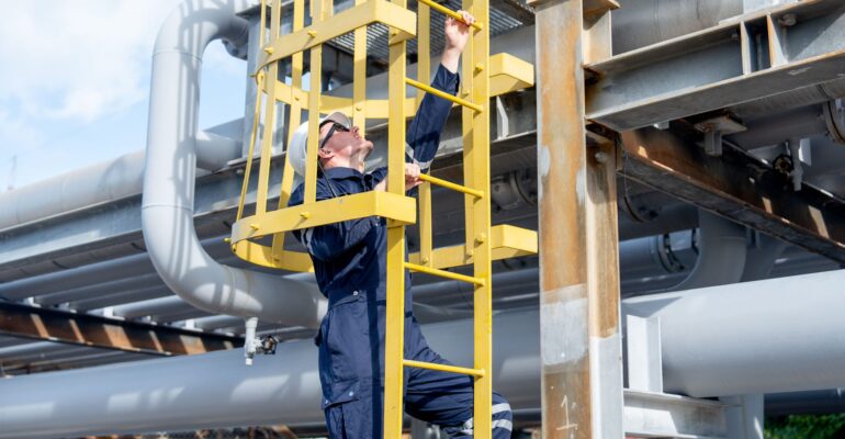 Factory engineer or technician worker climb up on stair of  petrochemical gas pipeline to work or maintenance in workplace.